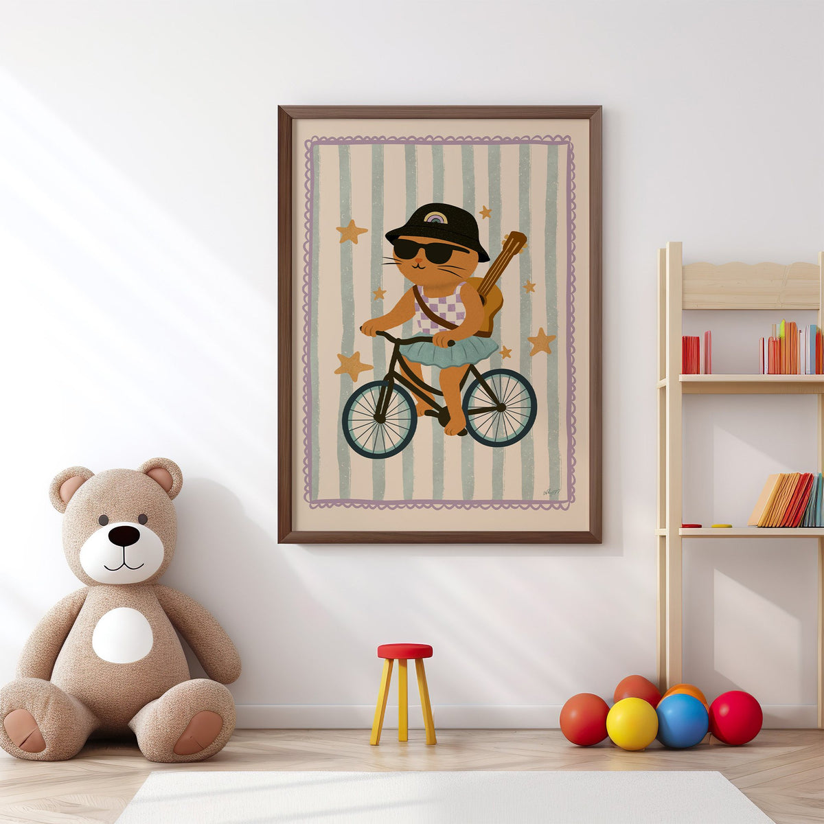 Orange cat on bicycle with ukulele nursery print in a walnut frame above a big teddy bear by a bookshelf