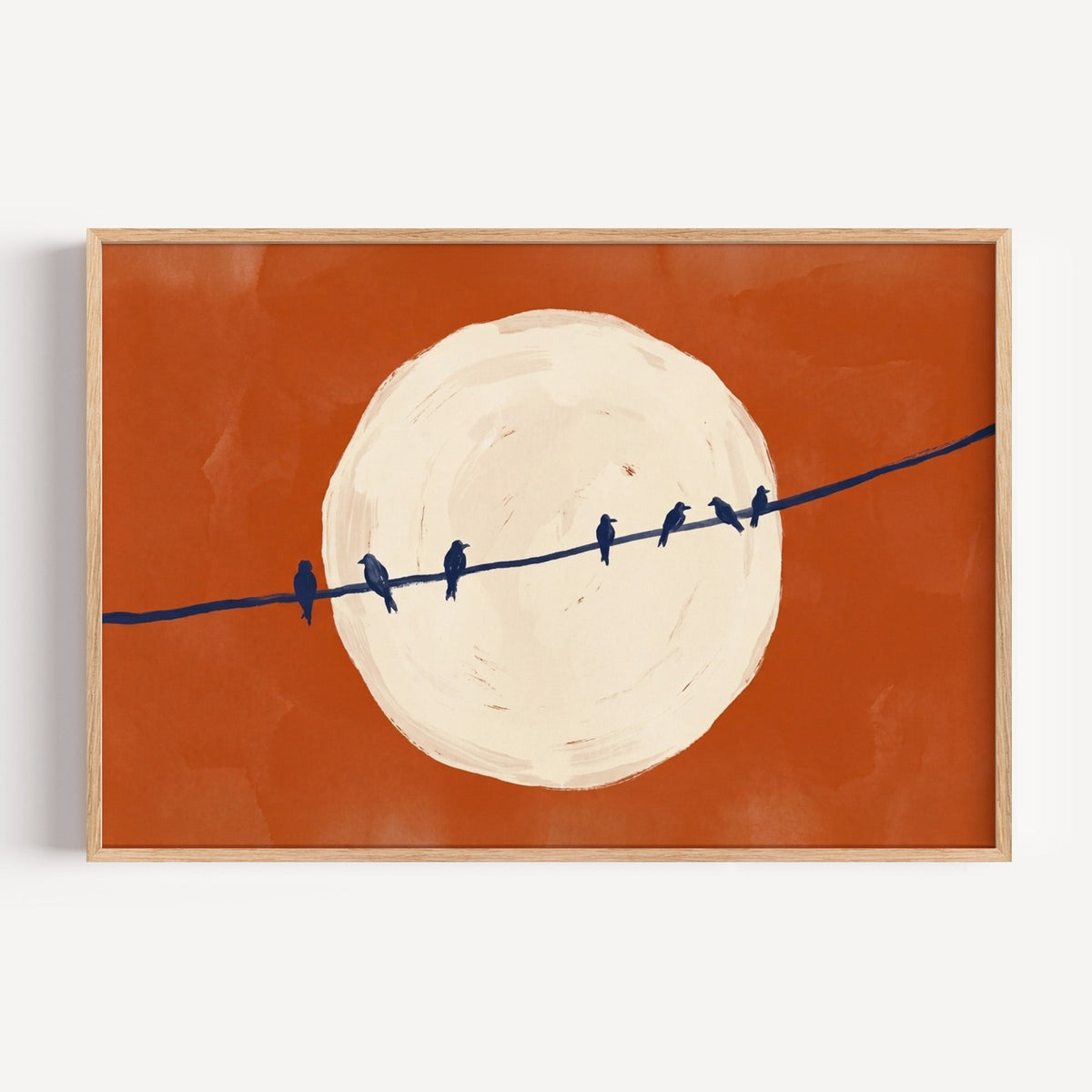 Birds on a wire moon print in a light oak frame on a plain white wall