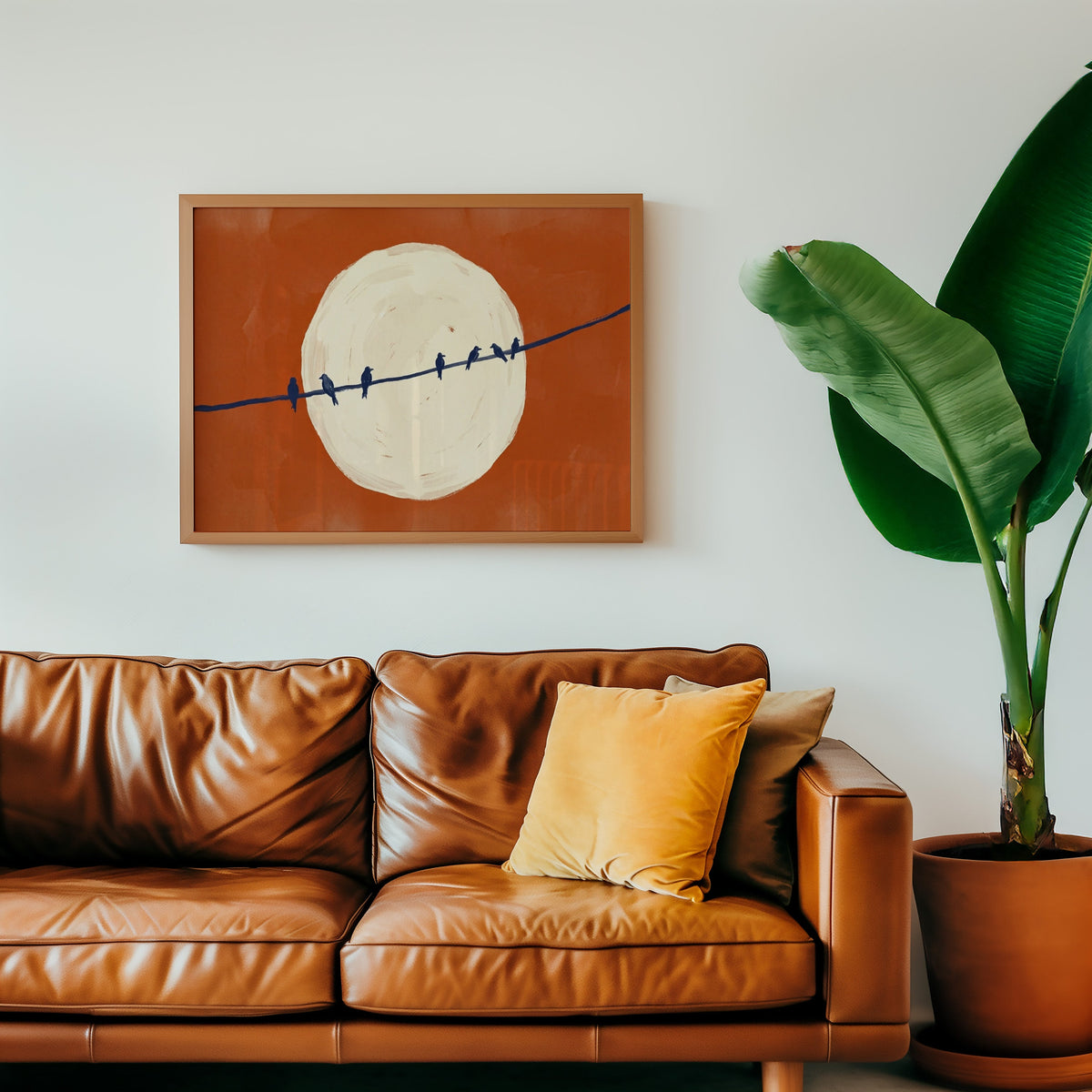 Rust and navy bird print in an oak frame above a cognac leather sofa