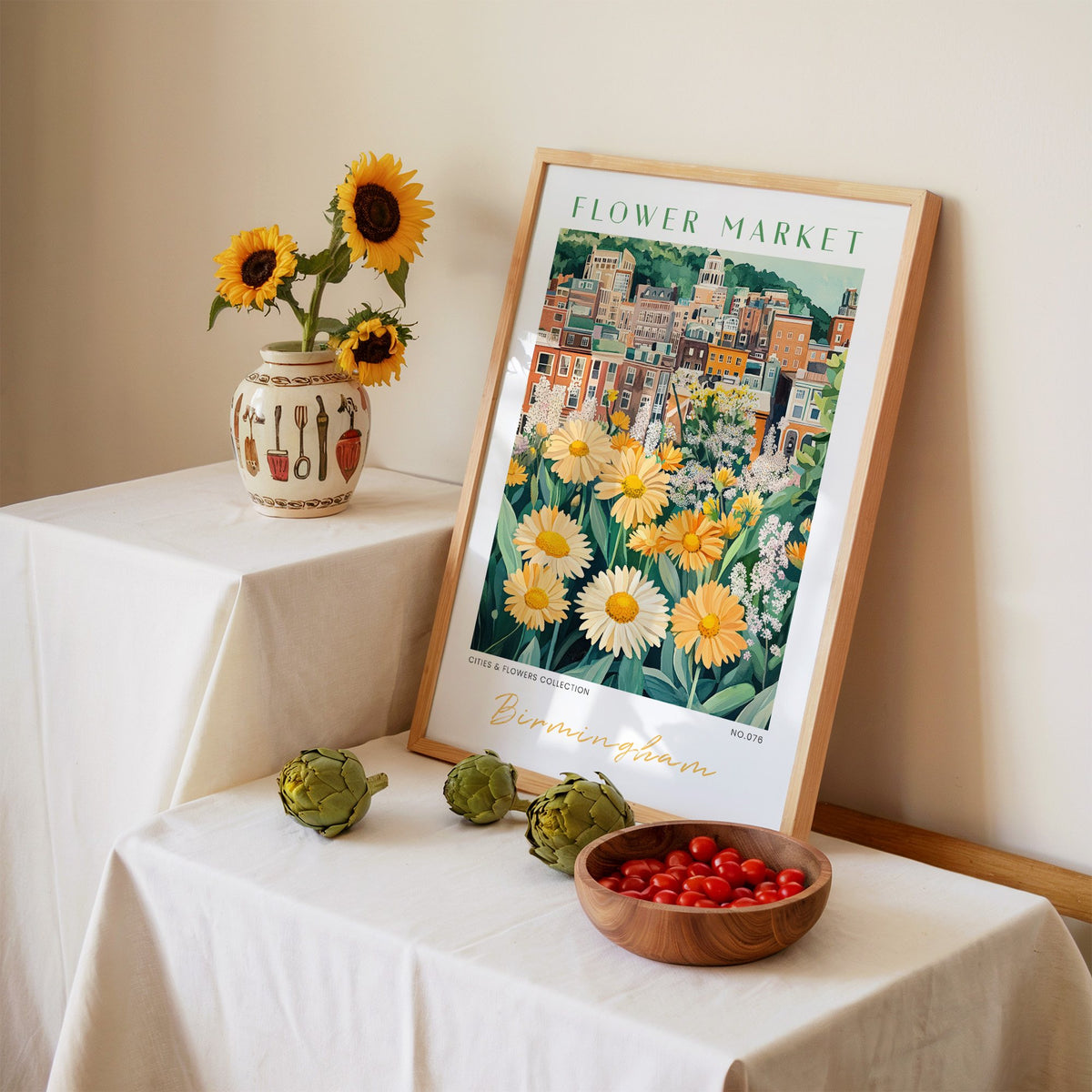 Birmingham flower market print in an oak frame leaning on a linen-draped table beside a vase of sunflowers