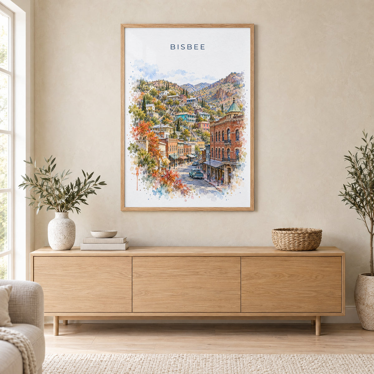 Bisbee watercolor print in an oak frame above a light wood sideboard in a Scandinavian living room