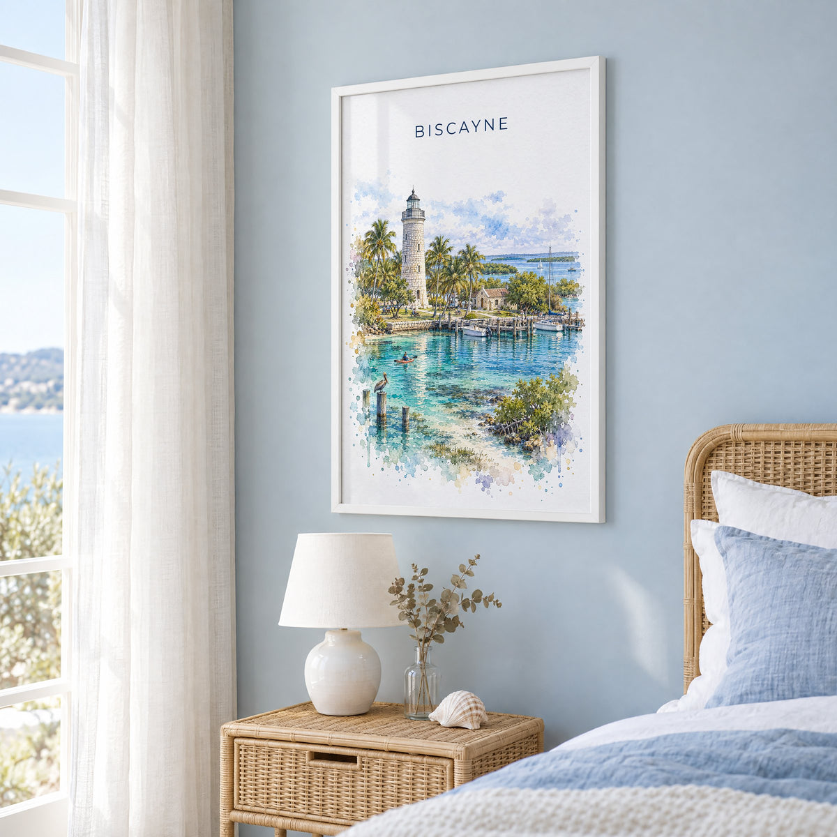 Biscayne National Park watercolor print in a white frame on a pale blue wall beside a rattan bed in a coastal bedroom