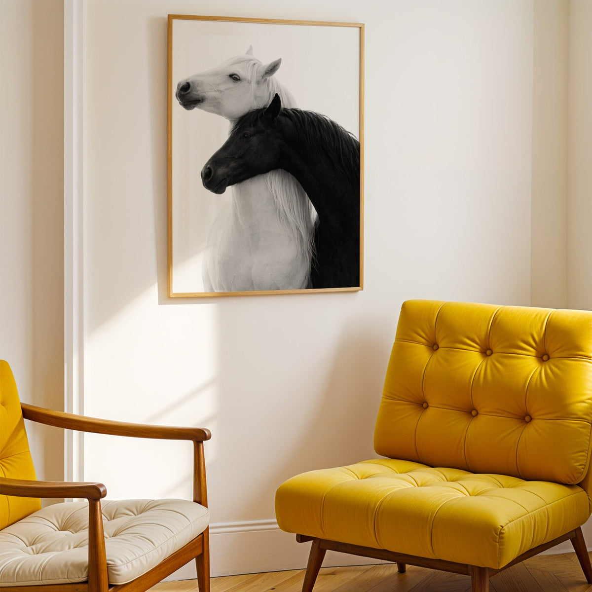 White horse and black horse necks crossed print shown in a gold frame above a mustard yellow tufted armchair