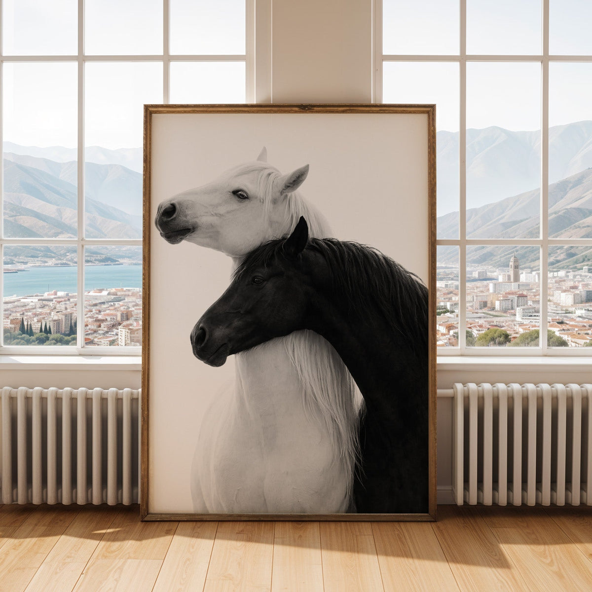 White horse and black horse necks crossed print shown in an antique gold frame by tall windows with a sea view