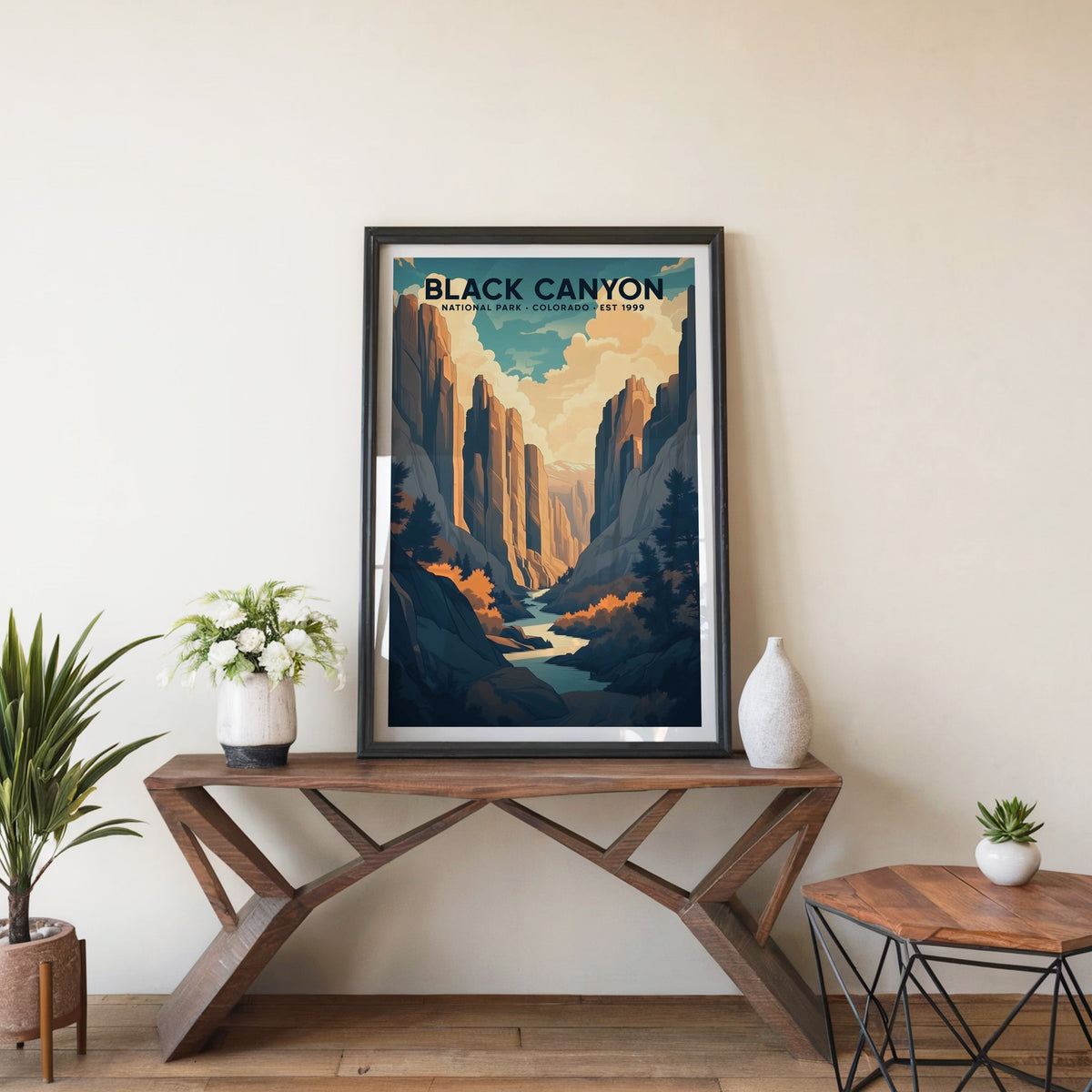 Black Canyon poster in a black frame on an entryway console table with white flowers and a yucca