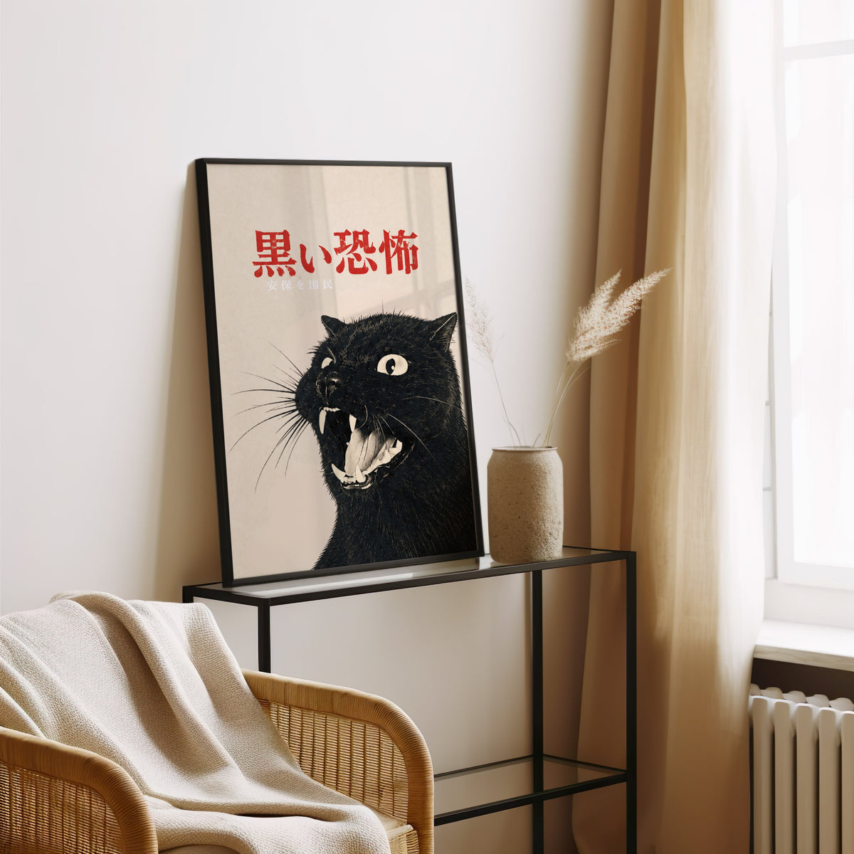 Hissing black cat kanji poster in a black frame leaning on a glass console beside pampas grass