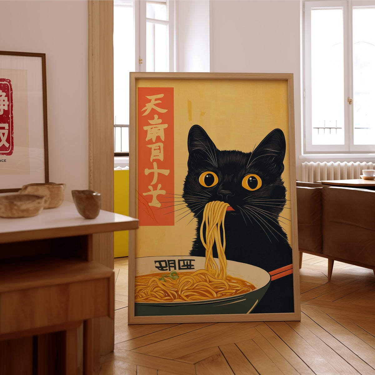 Black cat slurping ramen print in an oak frame on the parquet floor of a sunlit living room