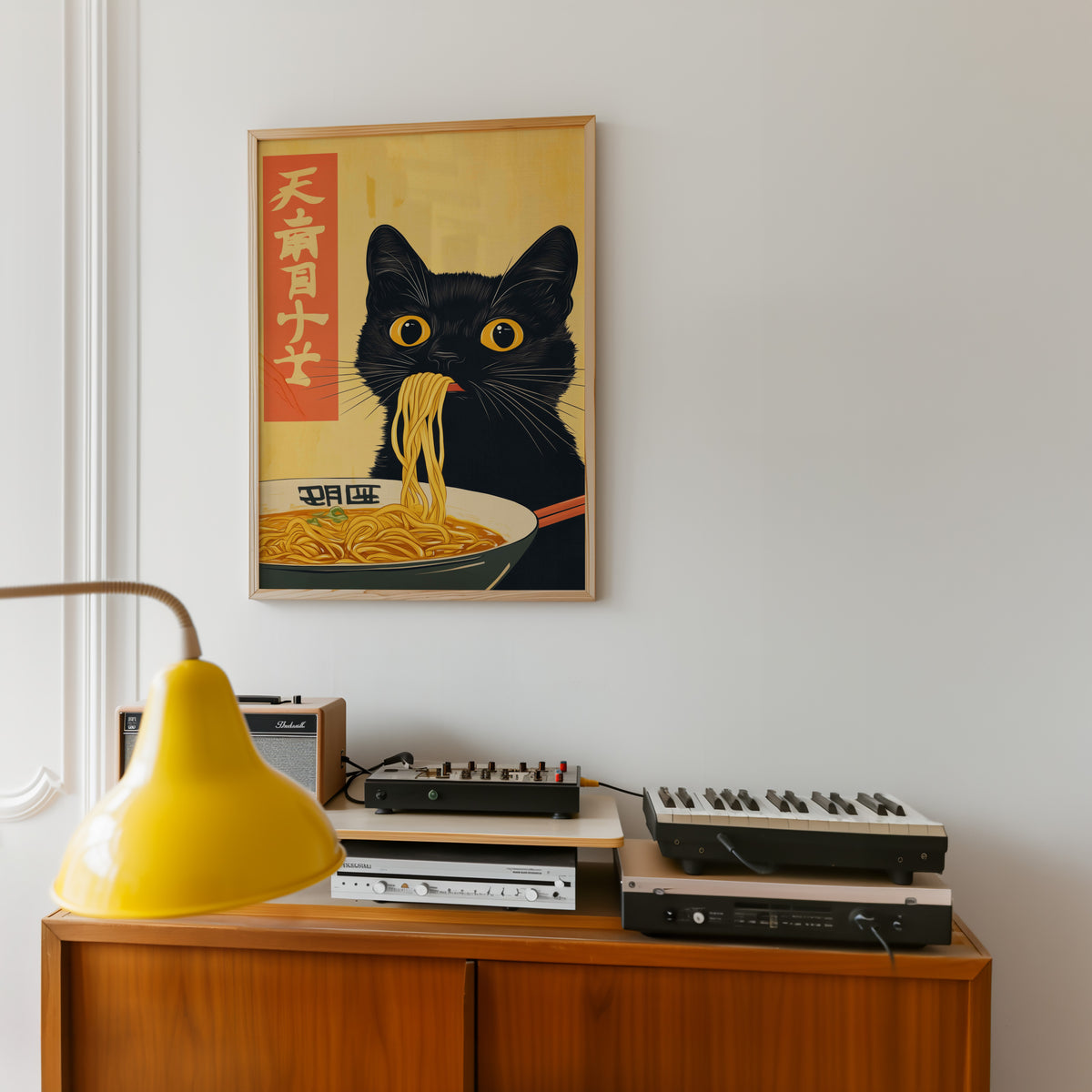 Black cat slurping ramen print in an oak frame above a teak sideboard with vintage hi-fi