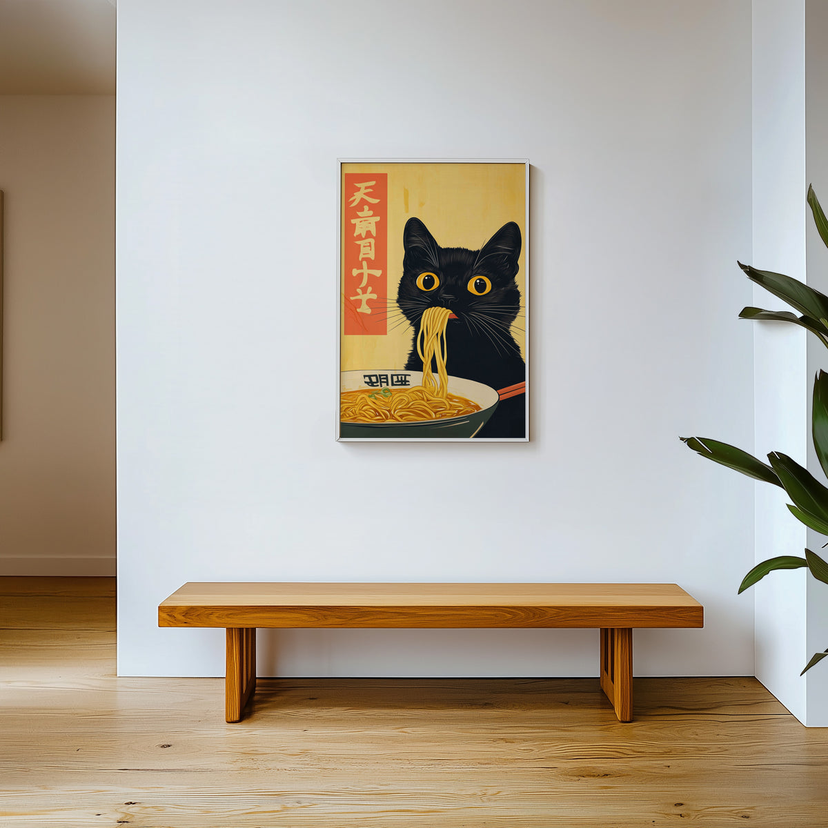Black cat slurping ramen print shown in a white frame above a wooden entryway bench