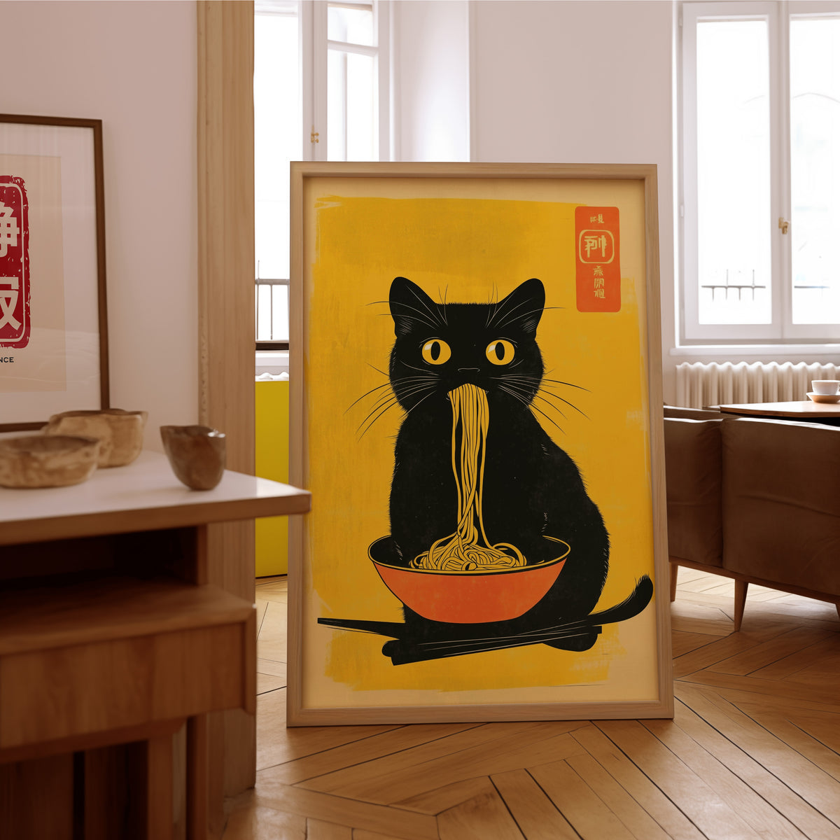 Black cat noodles orange bowl print in an oak frame on the parquet floor of a sunlit living room