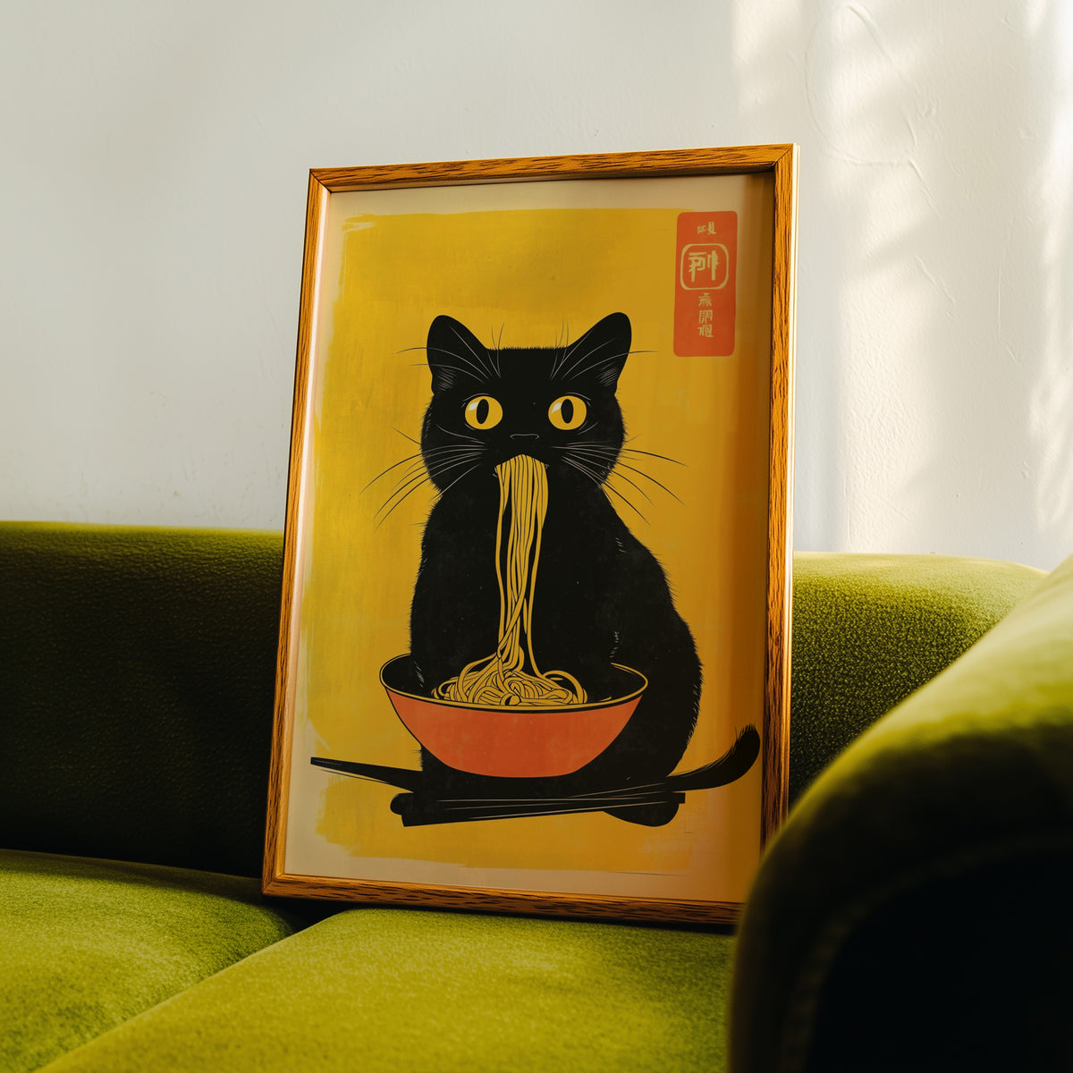 Black cat noodles orange bowl print in an oak frame propped on a green velvet sofa