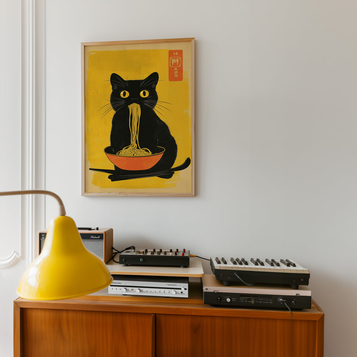 Black cat noodles orange bowl print in an oak frame above a teak sideboard with vintage hi-fi