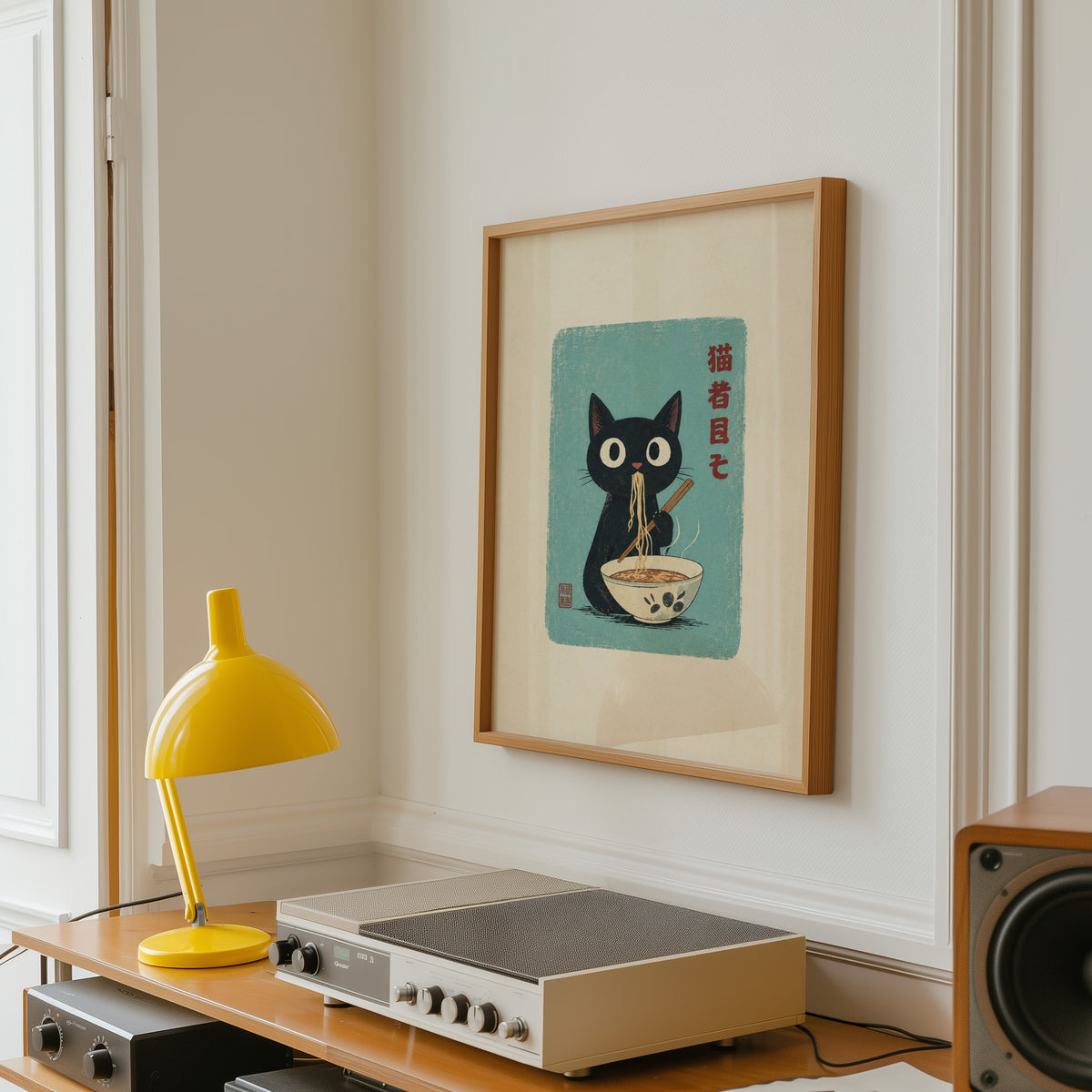 Black cat ramen teal poster in an oak frame above a vintage hi-fi shelf with a yellow desk lamp