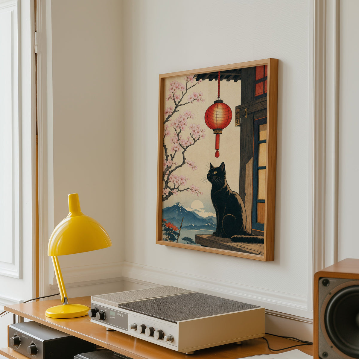 Black cat and red lantern poster in an oak frame above a vintage hi-fi shelf with a yellow desk lamp