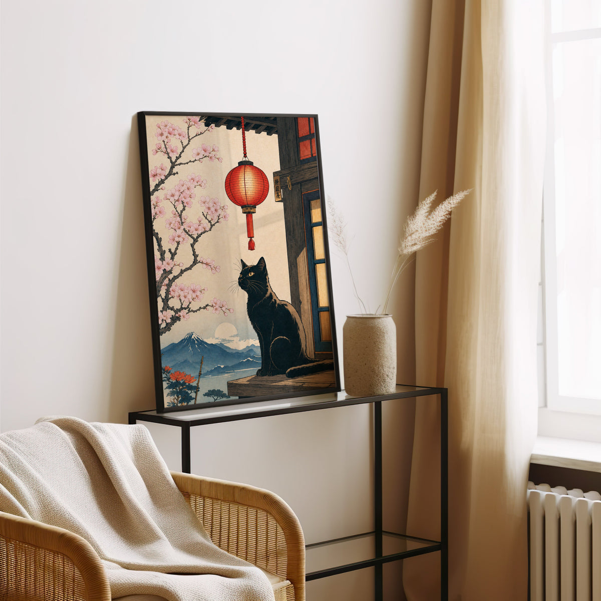 Black cat and red lantern poster in a black frame leaning on a glass console beside pampas grass