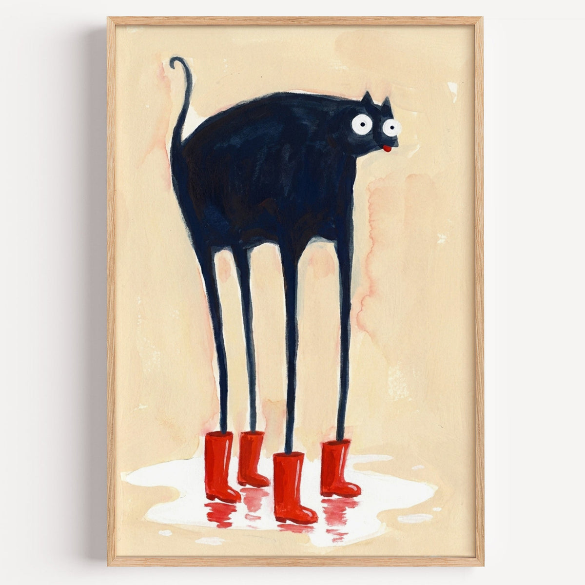 Black cat in red rain boots print in a light oak frame on a plain white wall