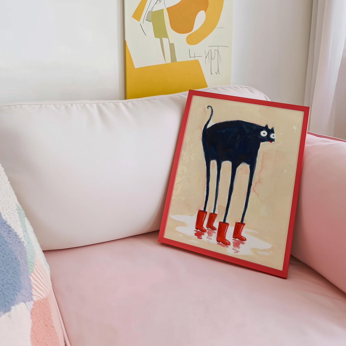 Rainy day black cat print shown in a red frame leaning on a blush pink sofa