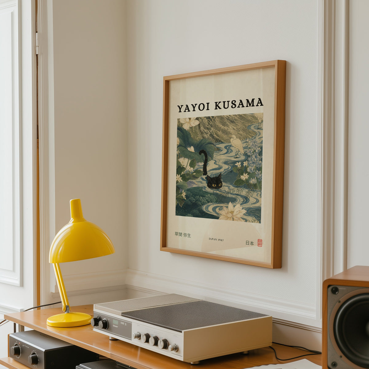 Black cat swimming lotus river poster in an oak frame above a vintage hi-fi shelf with a yellow desk lamp