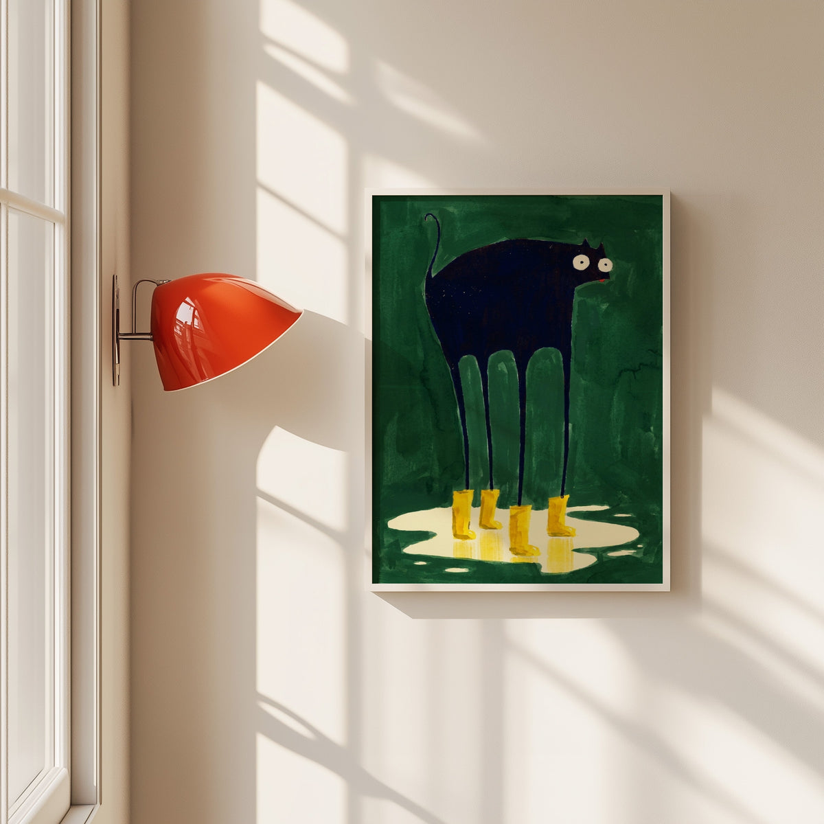 Black cat in yellow rain boots print in a white frame beside a red wall sconce