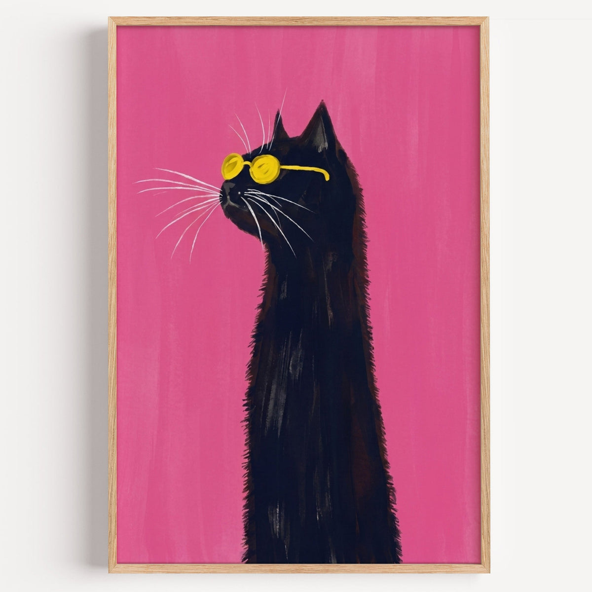 Black cat in yellow sunglasses print in a light oak frame on a plain white wall