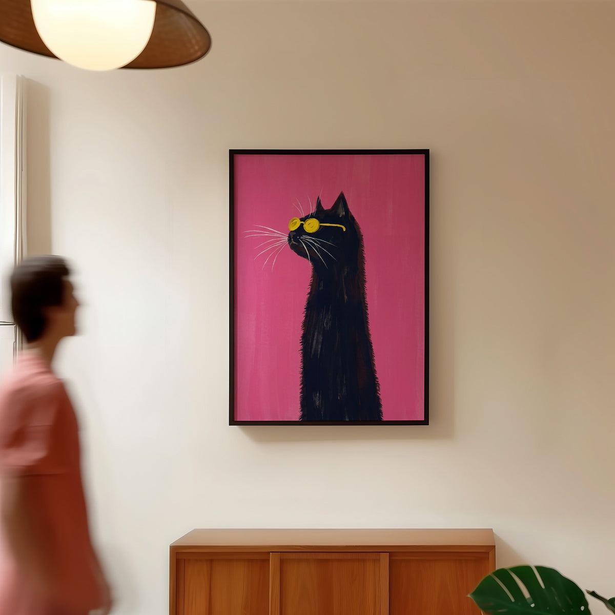 Fuchsia pink cat print in a black frame in a hallway under a rattan pendant