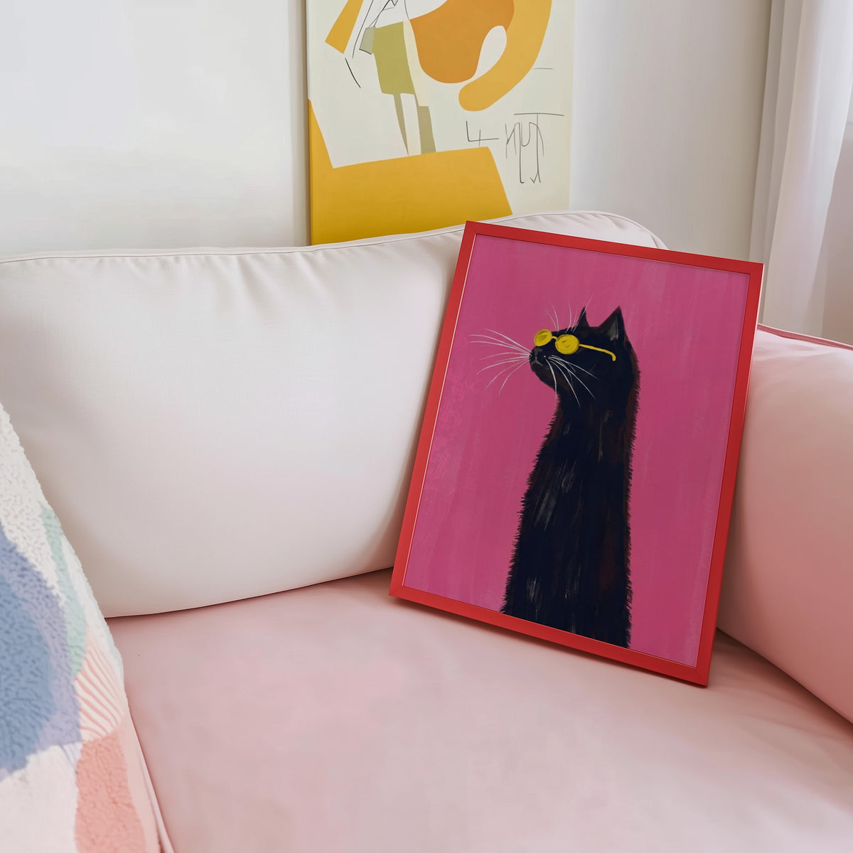 Long-necked black cat print shown in a red frame leaning on a blush pink sofa
