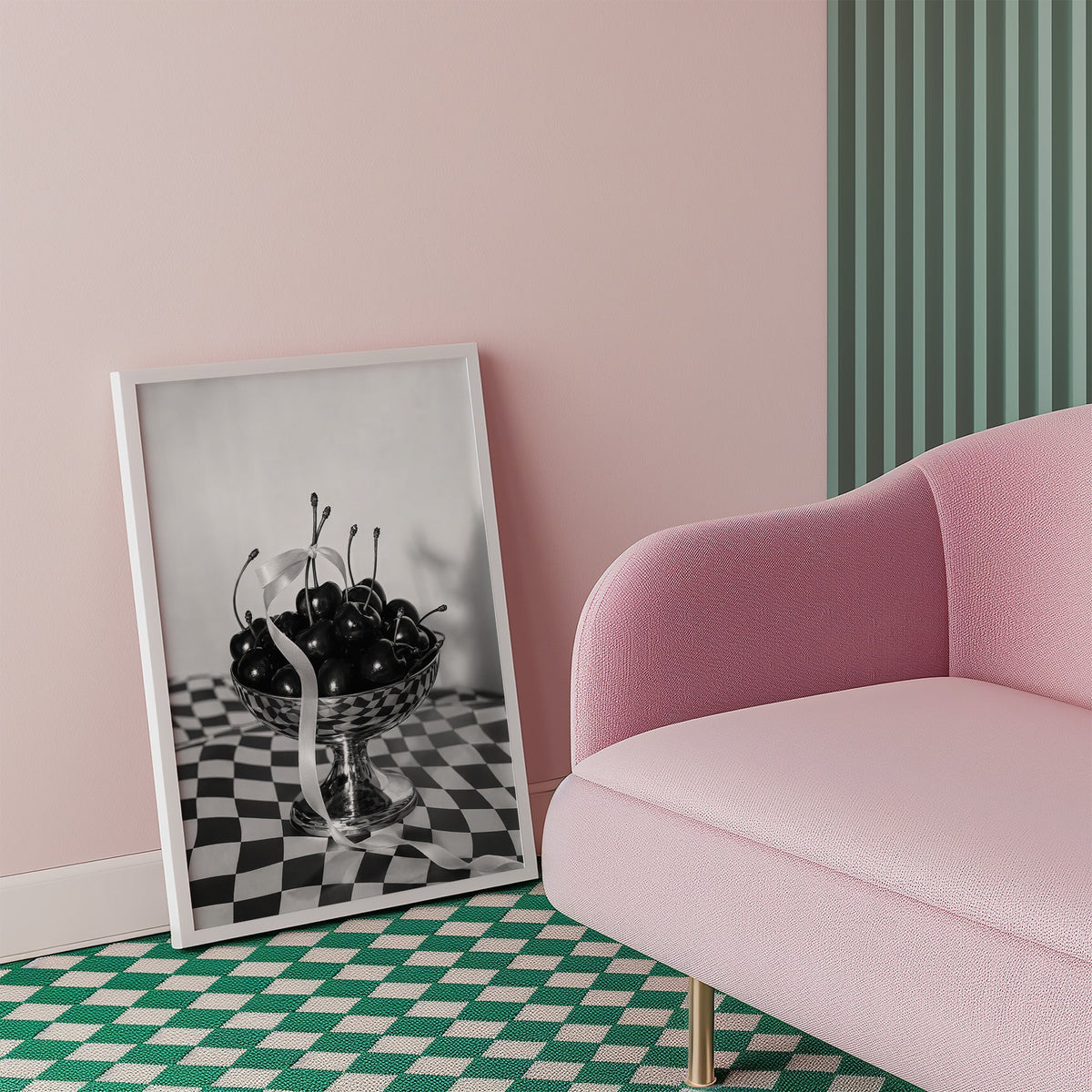 Black cherries in footed silver bowl print in a white frame beside a pink armchair on a checkered floor