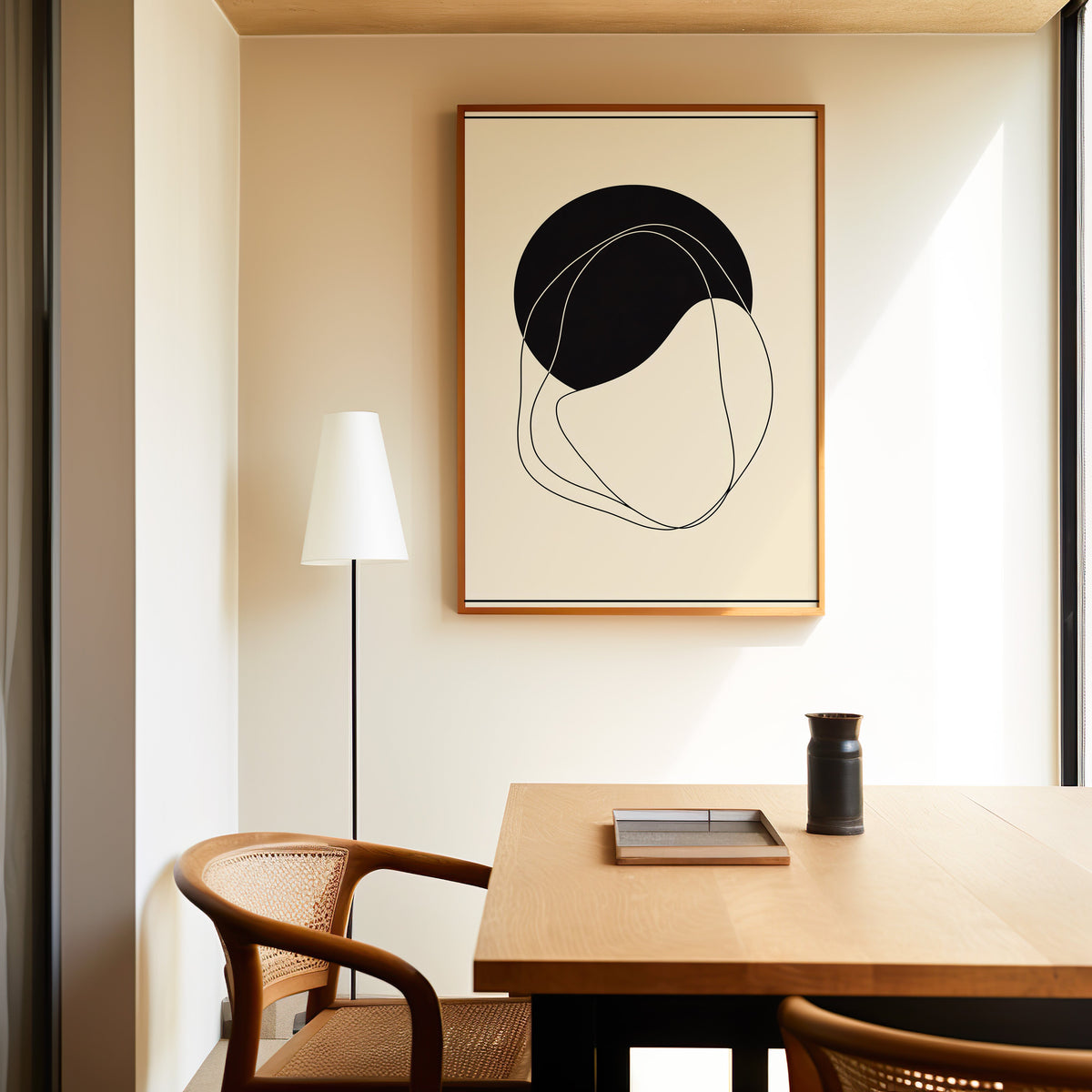 Black circle and organic line minimalist print in a slim oak frame above a dining table with a cane-back chair