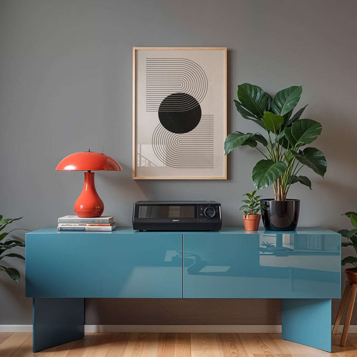 Black circle and S curve lines minimalist print in a light oak frame above a teal sideboard with a red mushroom lamp