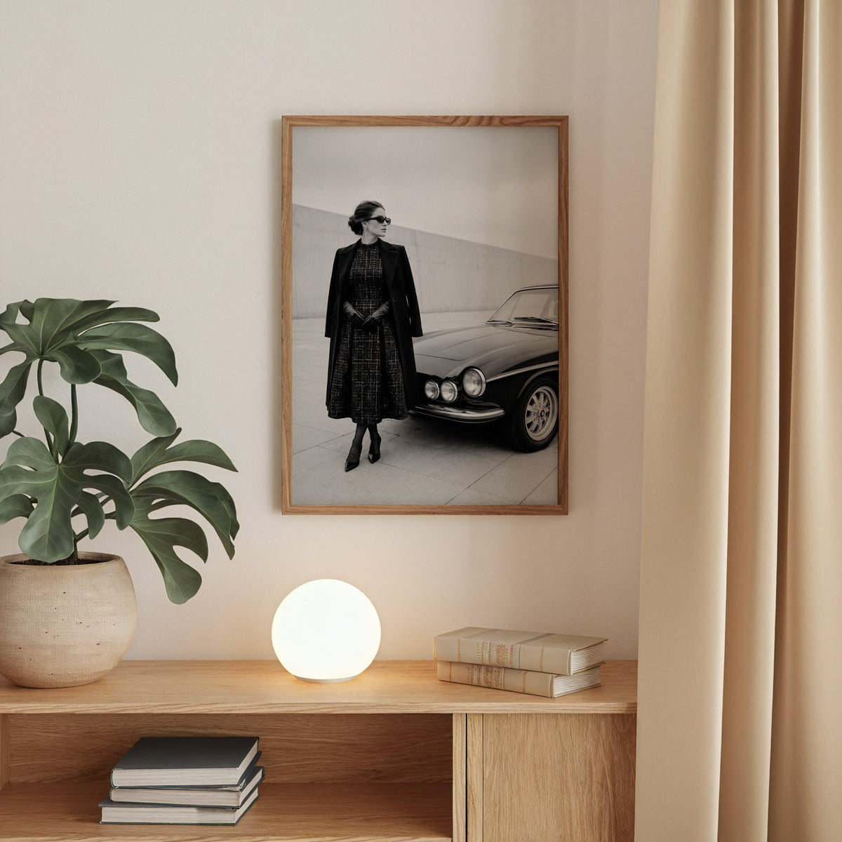 Black and white woman in tweed coat by classic car print in a walnut frame above an oak cabinet with a glowing globe lamp
