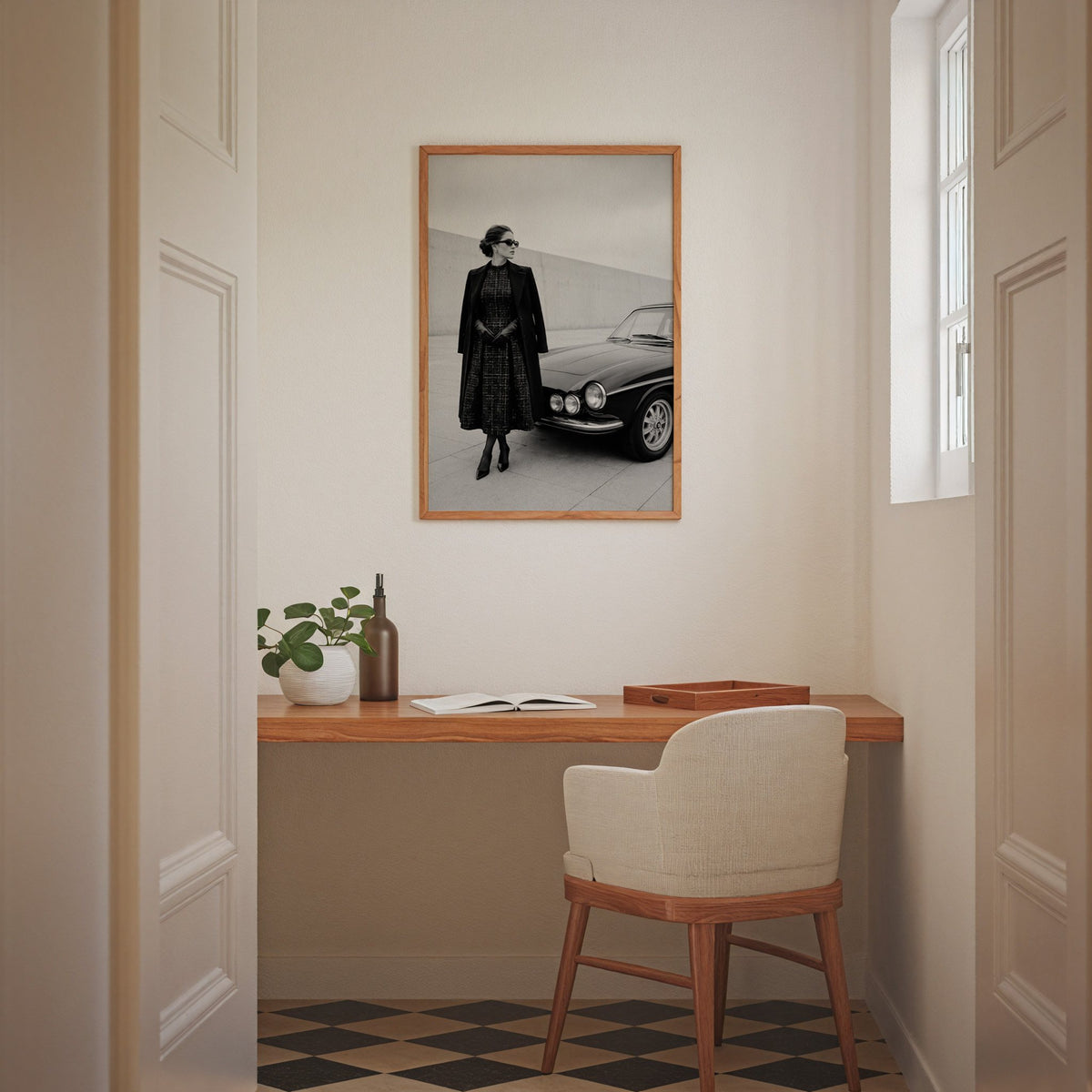 Black and white woman in tweed coat by classic car print in an oak frame above a home office desk nook