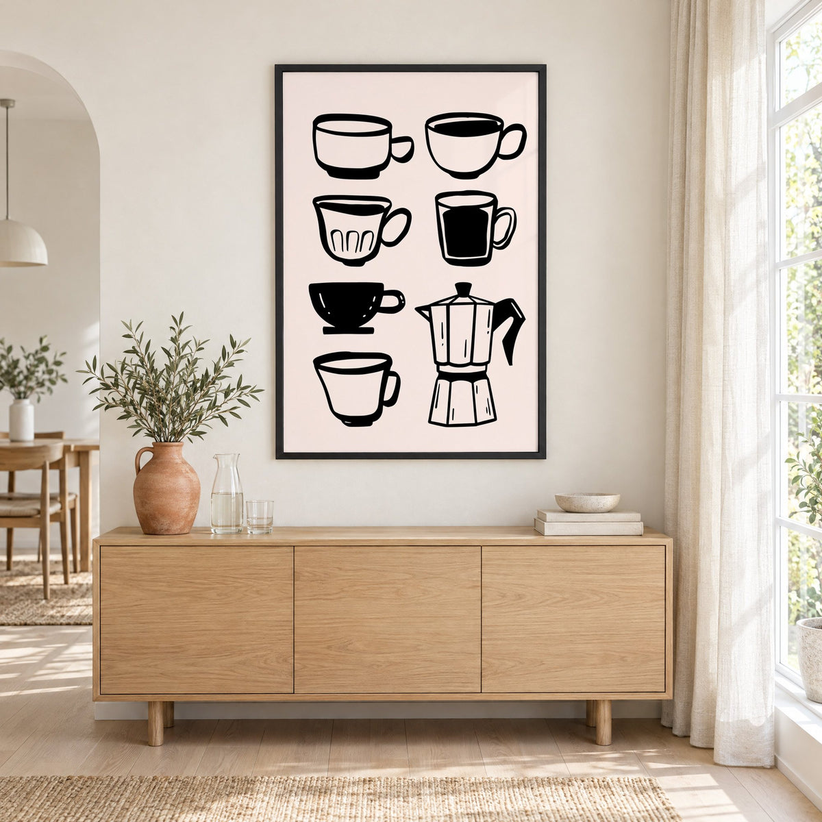Black coffee cups and moka pot print in a black frame above an oak sideboard with a terracotta vase of olive branches