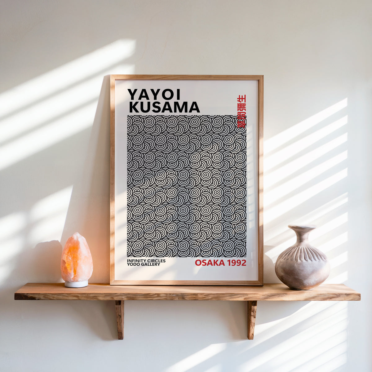 Yayoi Kusama inspired black concentric circles print on a wooden shelf beside a salt lamp and ceramic vase