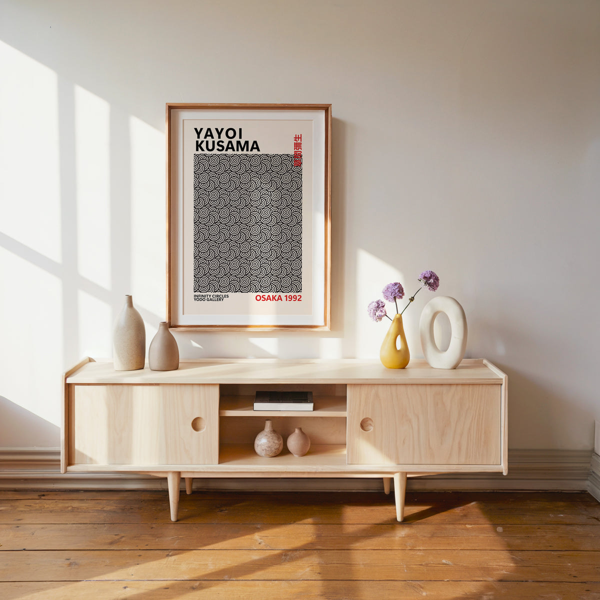 Yayoi Kusama inspired black concentric circles print with a white mat above a pale wood media console