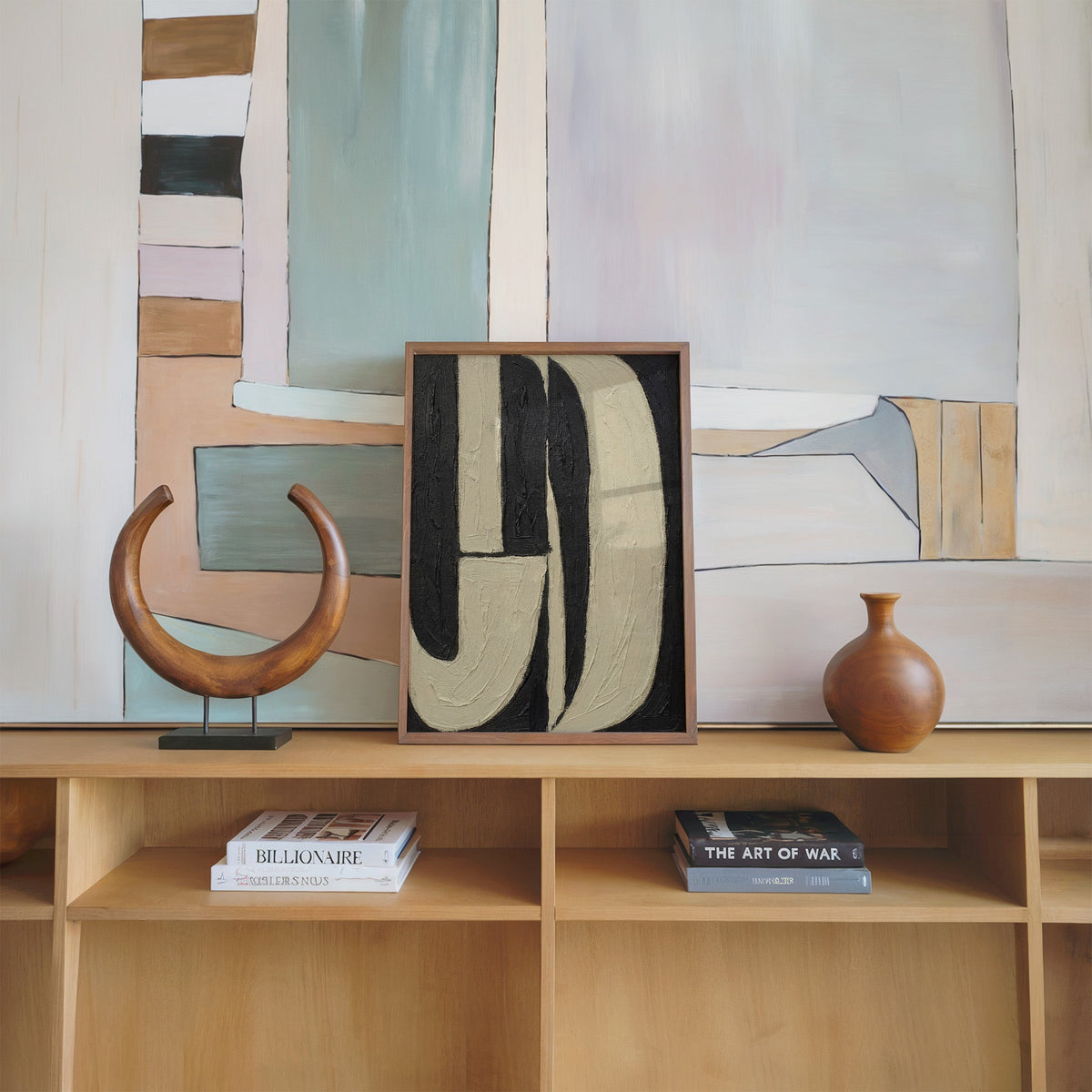 Black and cream J arch bands mid century print in a walnut frame on an oak shelf beside a wooden crescent sculpture