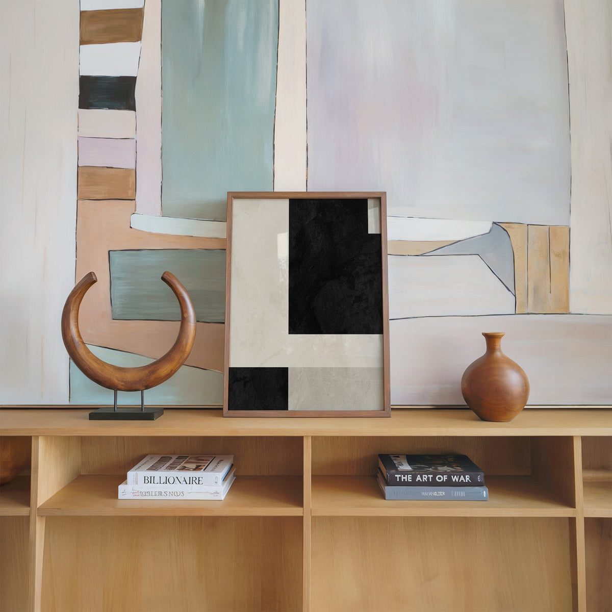 Black and cream offset plaster blocks print in a walnut frame on an oak shelf beside a wooden crescent sculpture