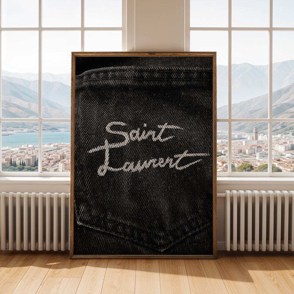 White script stitched on black denim pocket print shown in an antique gold frame by tall windows with a sea view
