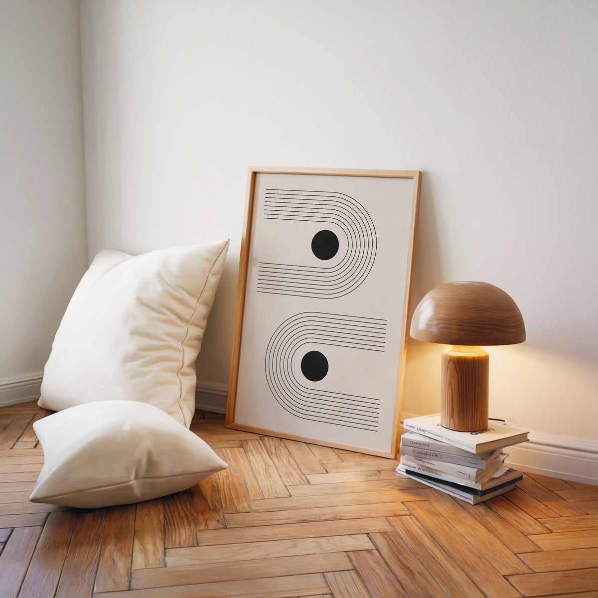 Black dots in sideways line arches print in a light wood frame on a herringbone floor by a wooden mushroom lamp