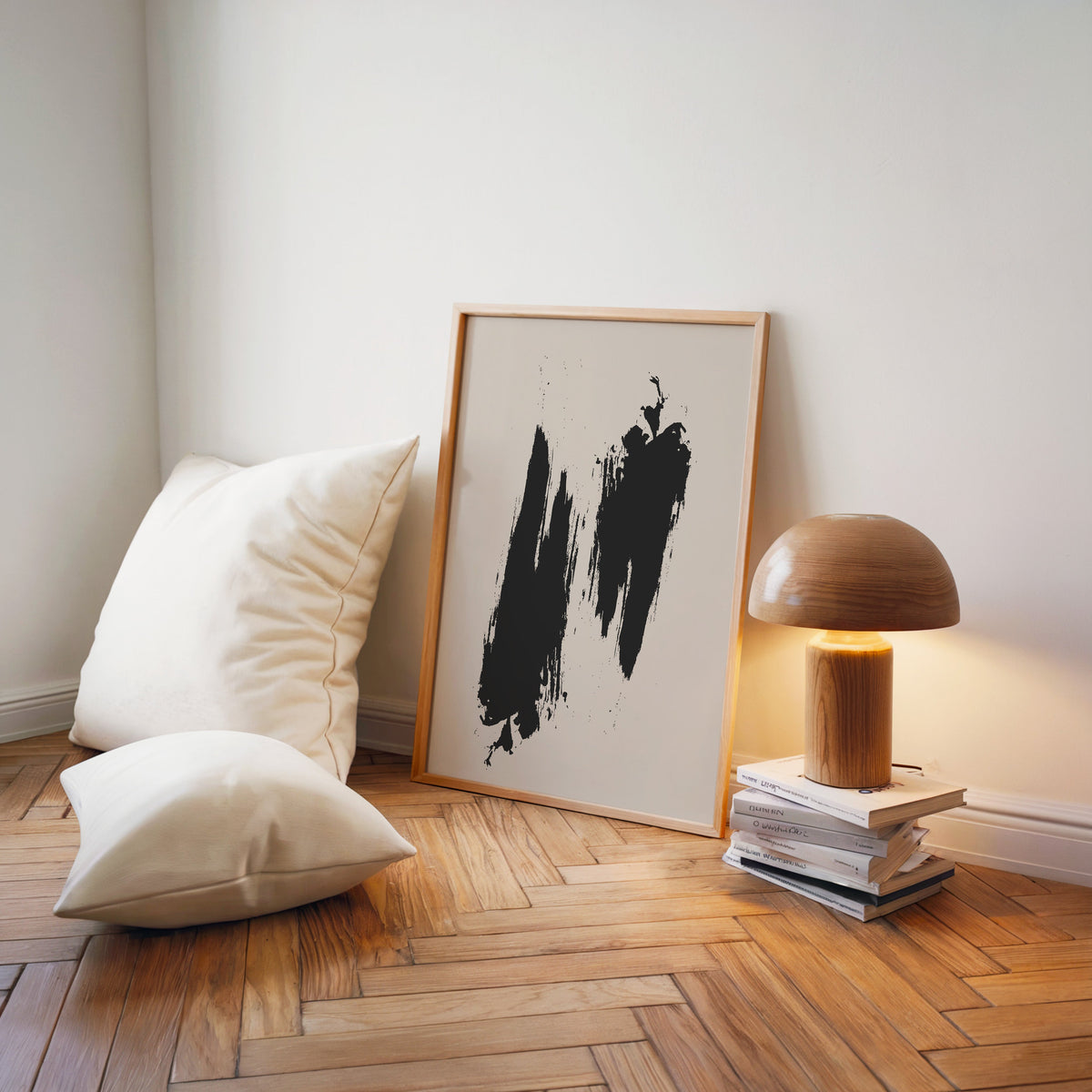 Black dry brush twin strokes minimalist print in a light wood frame on a herringbone floor by a wooden mushroom lamp