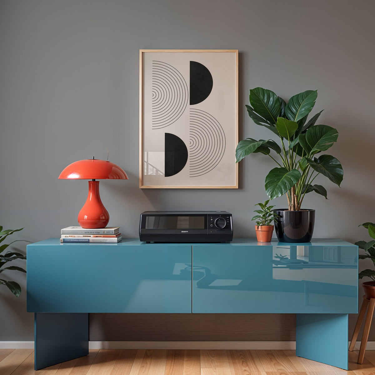 Black half circles and concentric rings print in a light oak frame above a teal sideboard with a red mushroom lamp