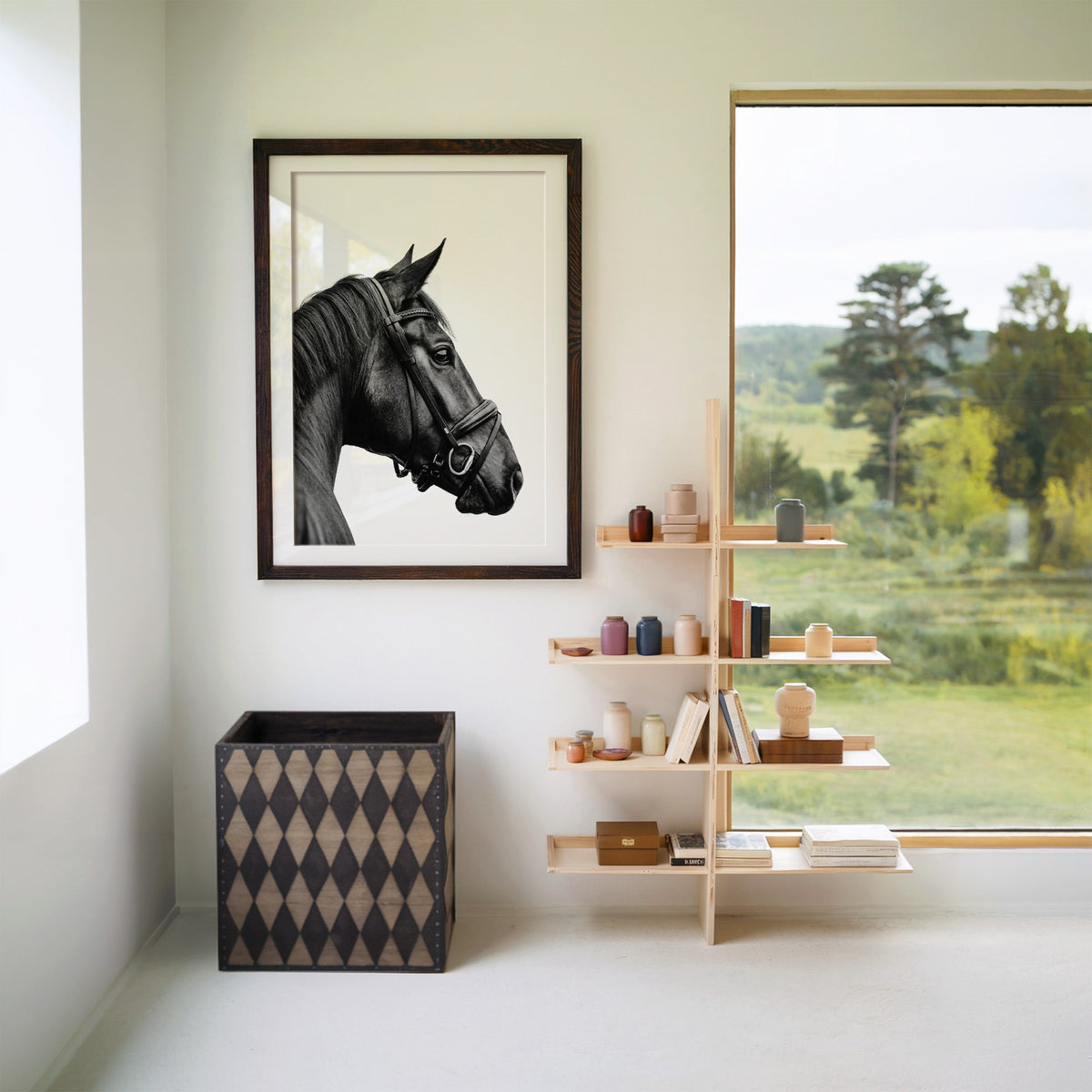 Black horse head in leather bridle profile print in a walnut frame with a white mat beside wooden shelves and a garden window