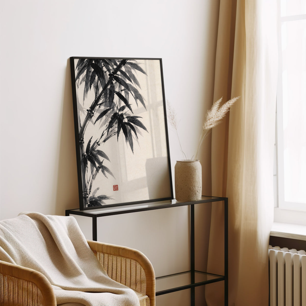 Black ink bamboo sumi-e poster in a black frame leaning on a glass console beside pampas grass