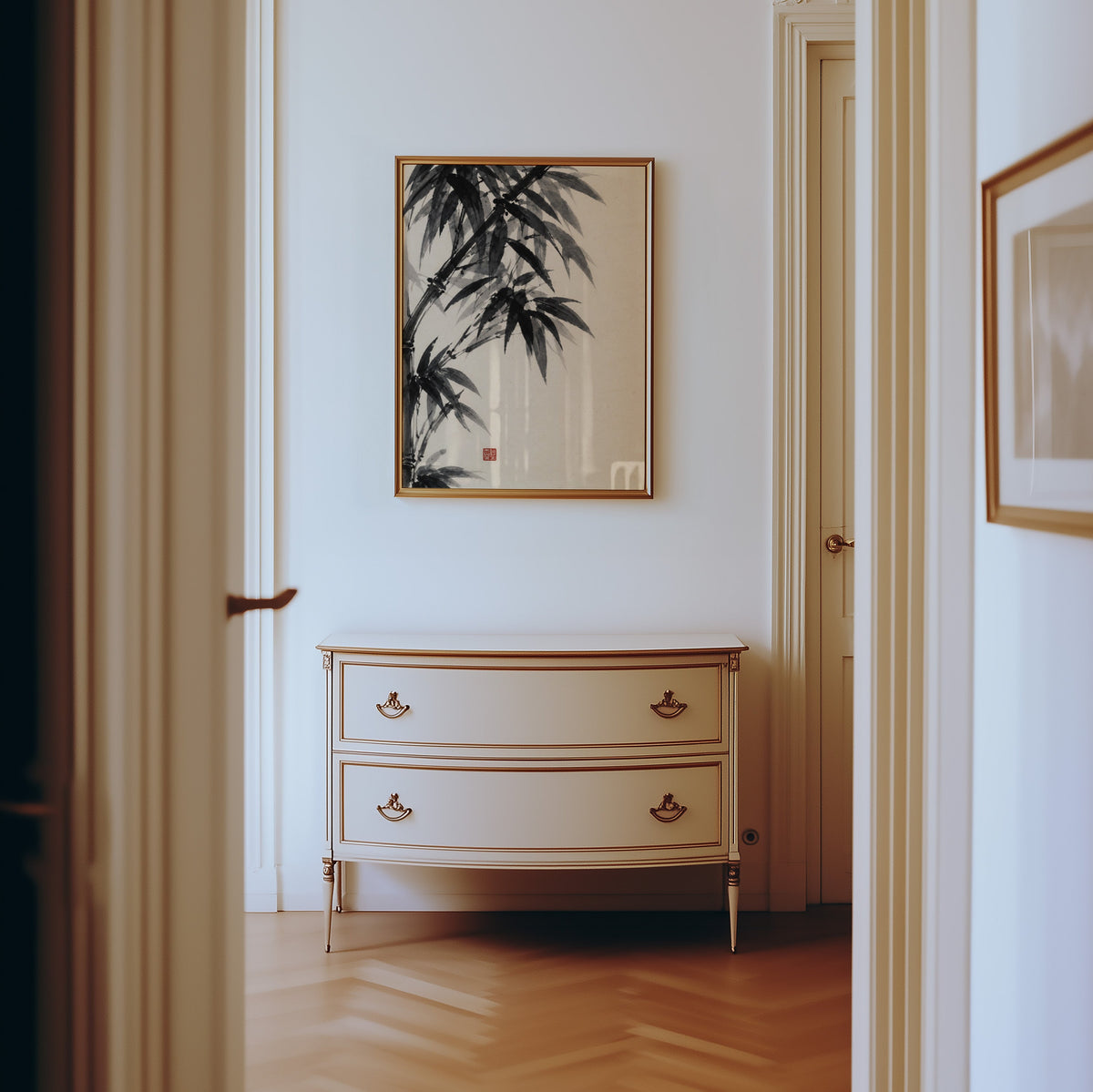 Black ink bamboo sumi-e poster shown in a gold frame in a hallway above a cream dresser