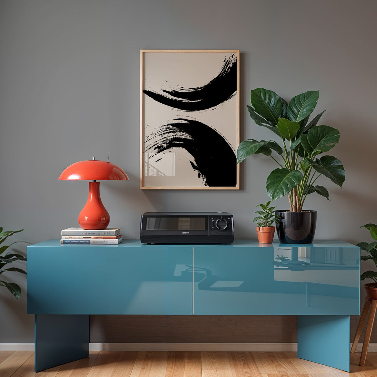 Black ink brush arcs abstract print in a light oak frame above a teal sideboard with a red mushroom lamp