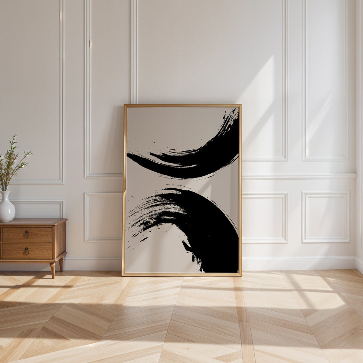 Black ink brush arcs abstract print shown in a gold frame leaning on a paneled white wall in sunlight