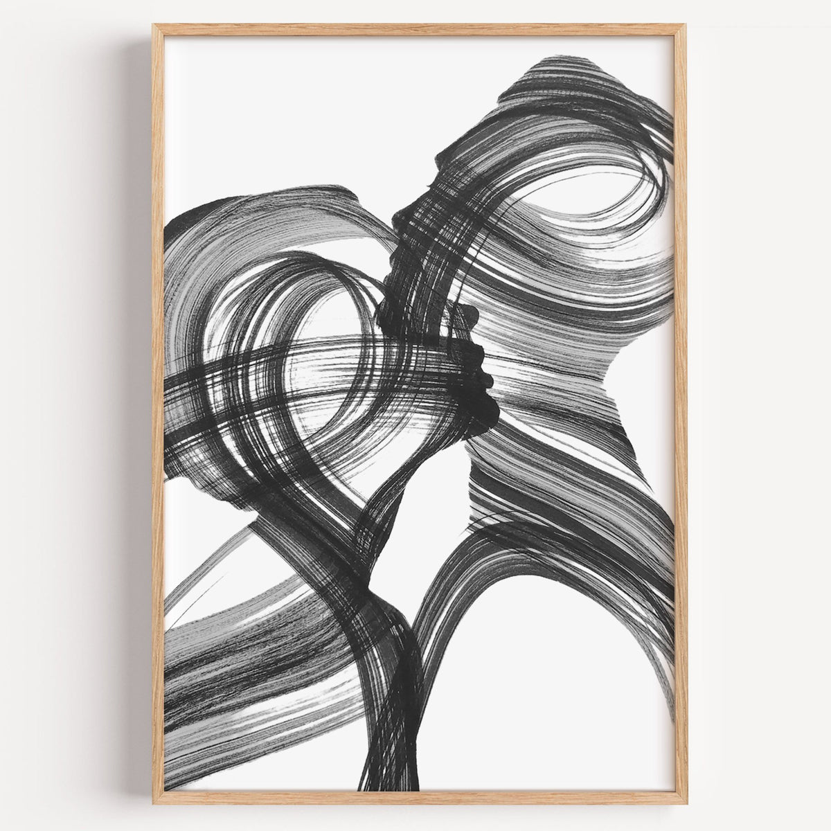 Black ink brush swirl abstract print in a light oak frame on a plain white wall