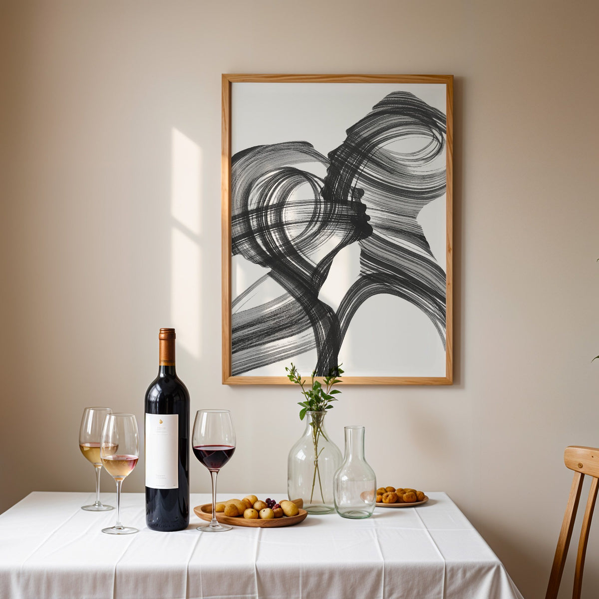 Black ink brush swirl abstract print in an oak frame above a table set with red wine and glasses