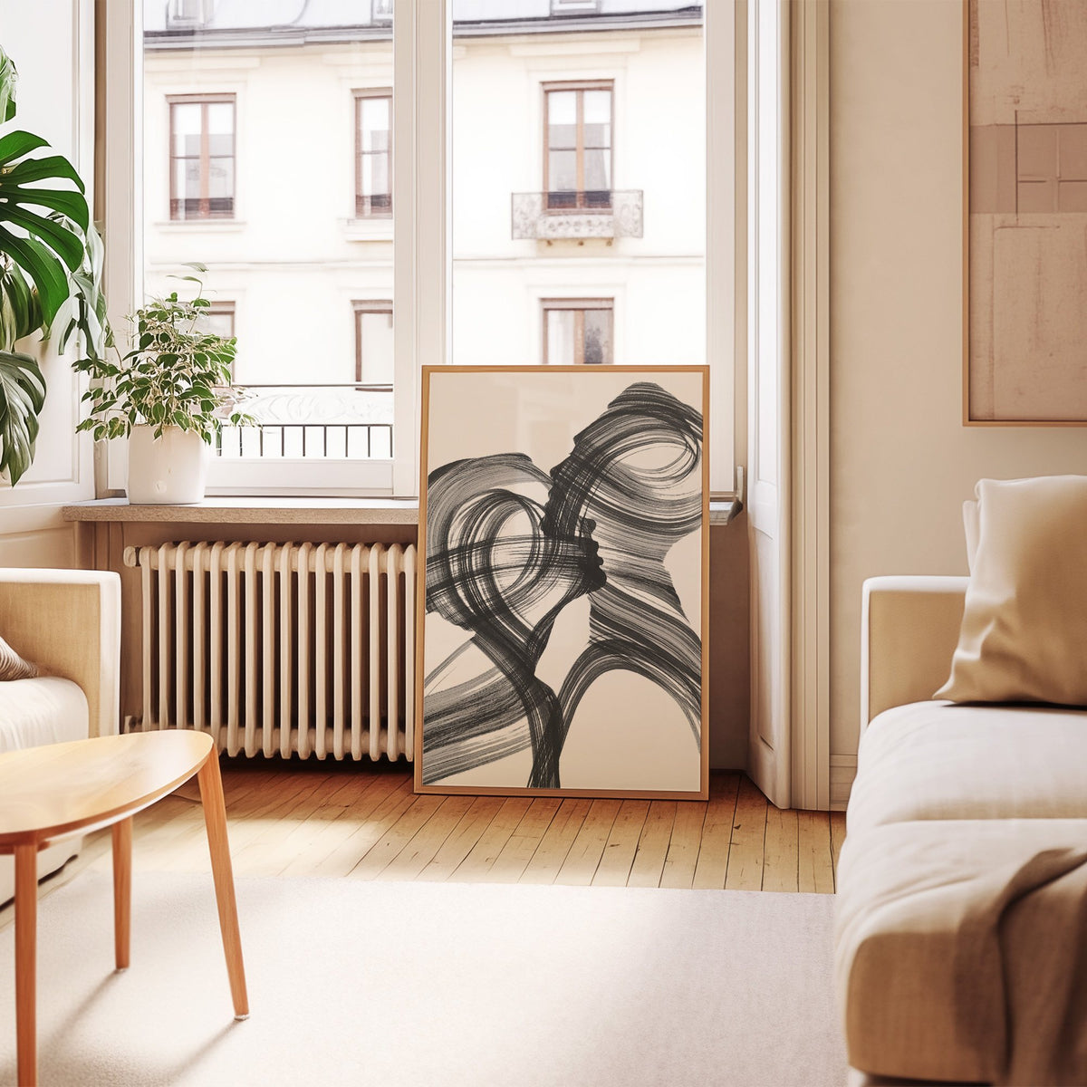 Black ink brush swirl abstract print in an oak frame leaning by a French window in a living room