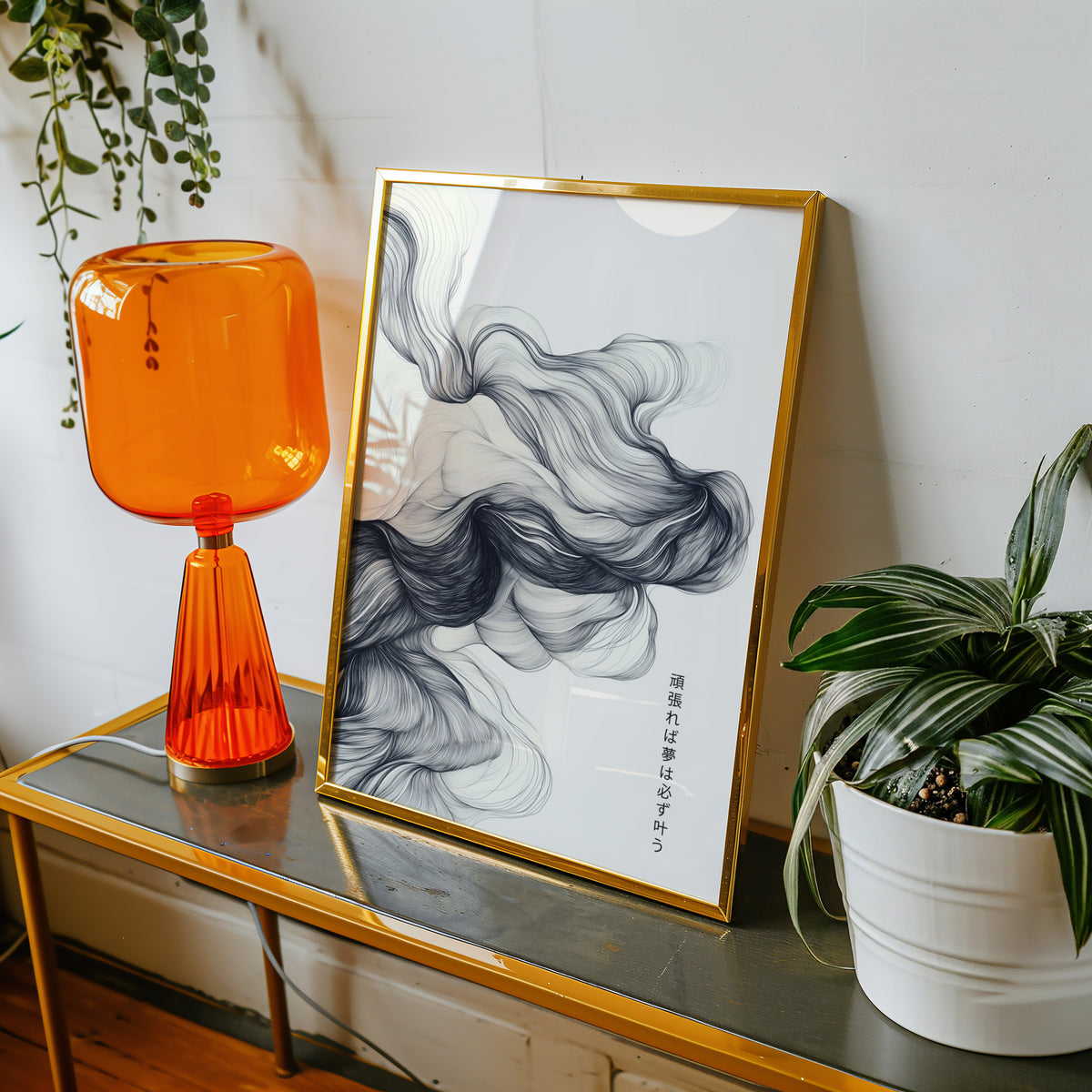 Black ink swirl dreams proverb print shown in a gold frame on a console beside an orange glass lamp