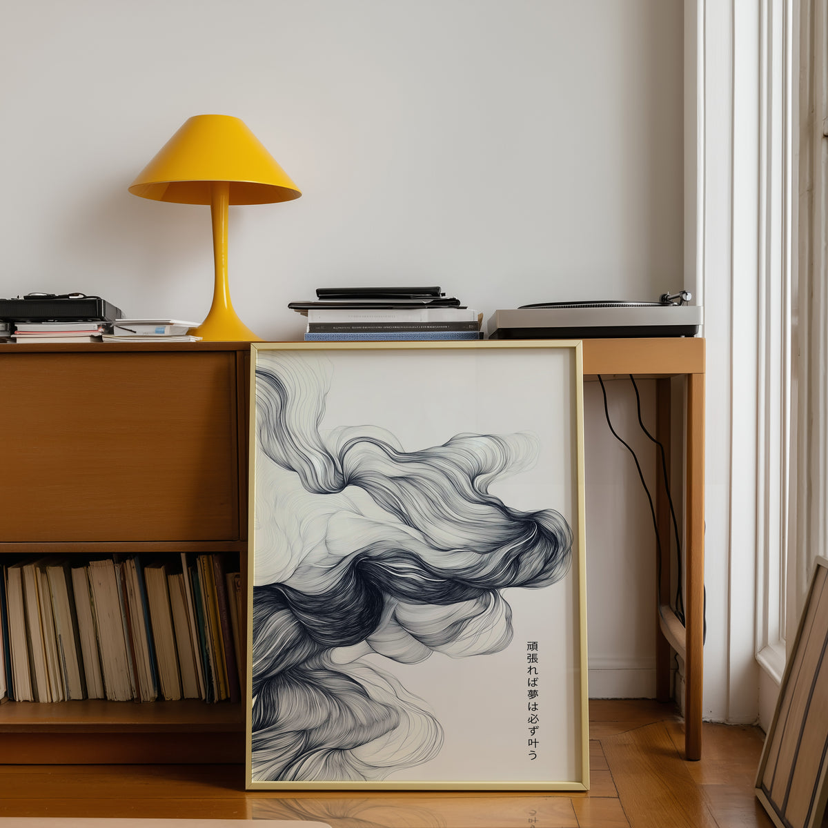 Black ink swirl dreams proverb print shown in a gold frame below a teak desk with a yellow lamp
